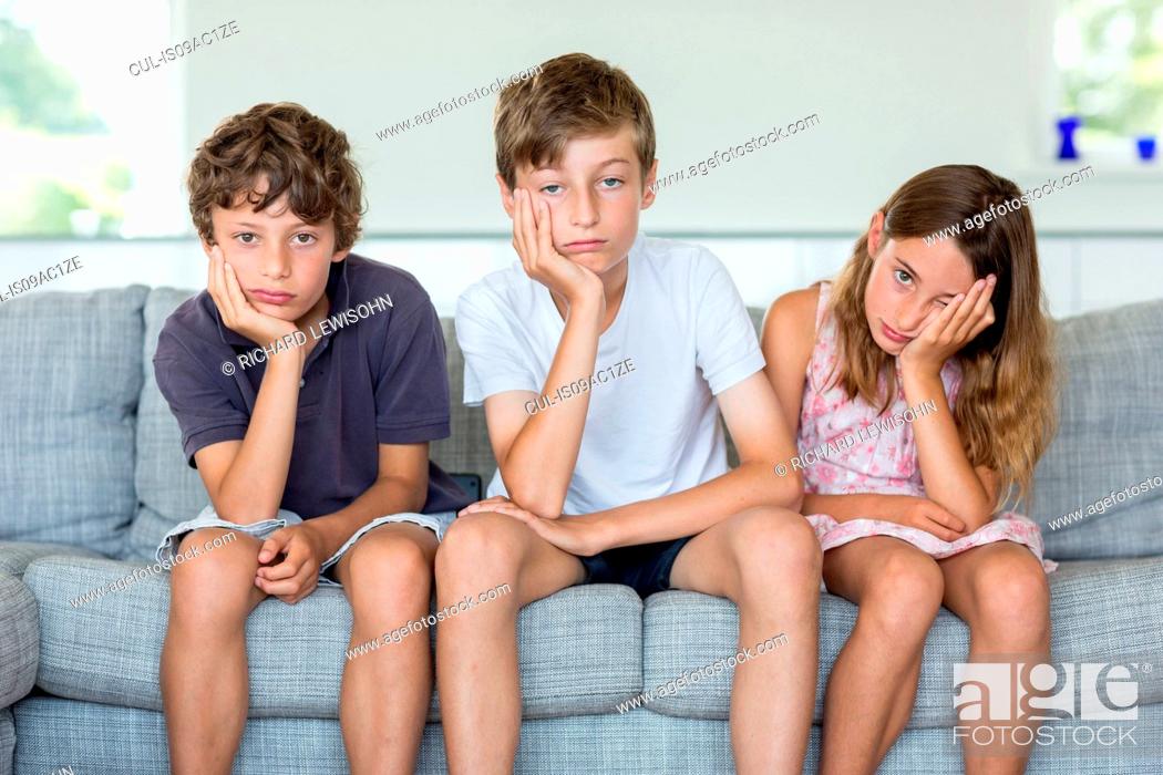 Stock Photo: Brothers and sister on sofa looking bored.
