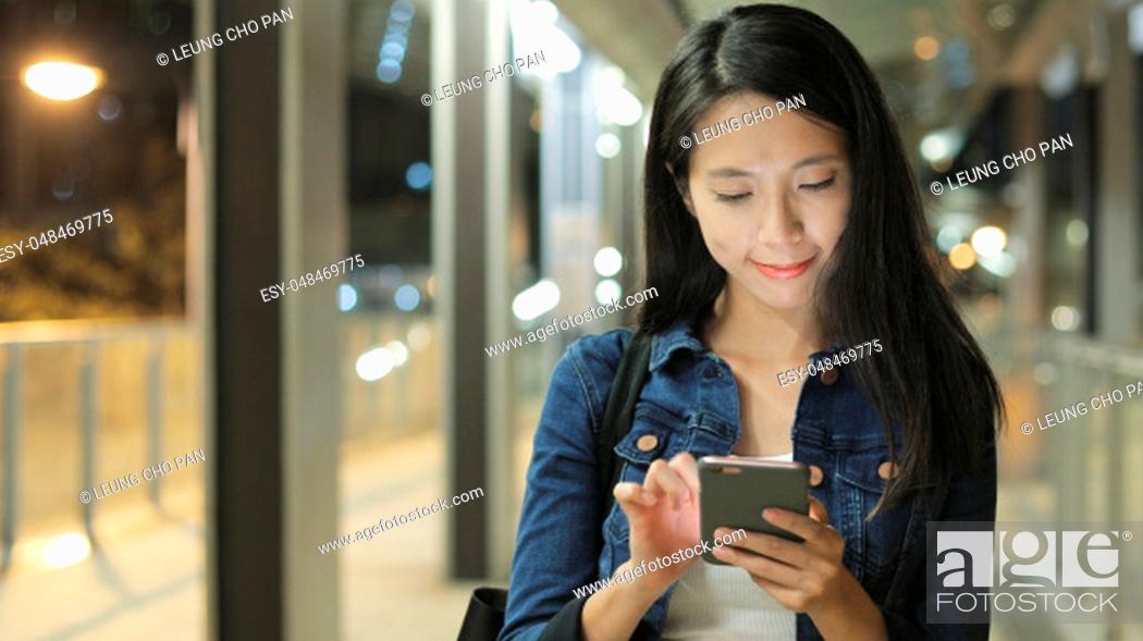 Stock Photo: Woman using mobile phone in city at night.