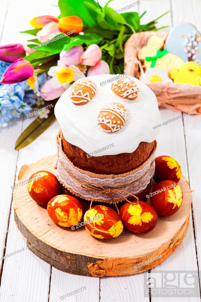 Stock Photo: Top view traditional Easter bread covered with sugar glaze and cookies in egg shape, tulip bouquet on background, blured.