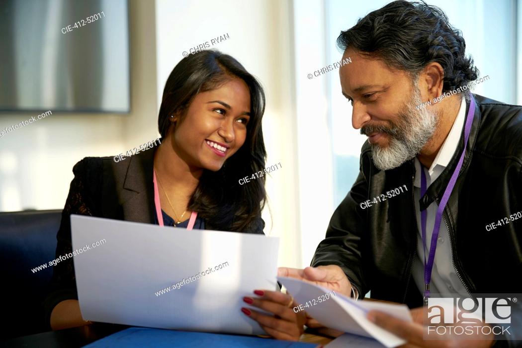 Stock Photo: Smiling business people discussing paperwork in meeting.