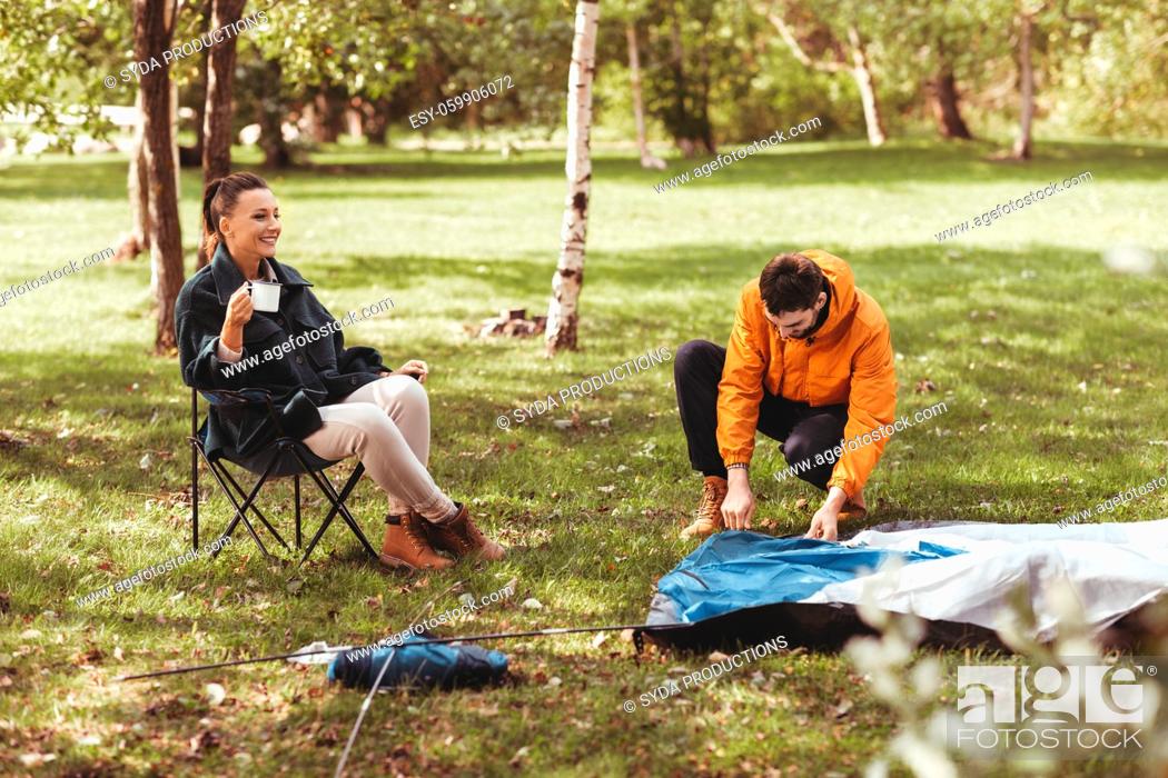 Stock Photo: happy couple setting up tent outdoors.