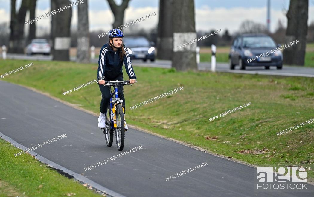Stock Photo: 22 January 2021, Brandenburg, Lebus: ILLUSTRATION: A girl rides on a newly built bicycle path along the federal highway 167 near Lebus in the district of.