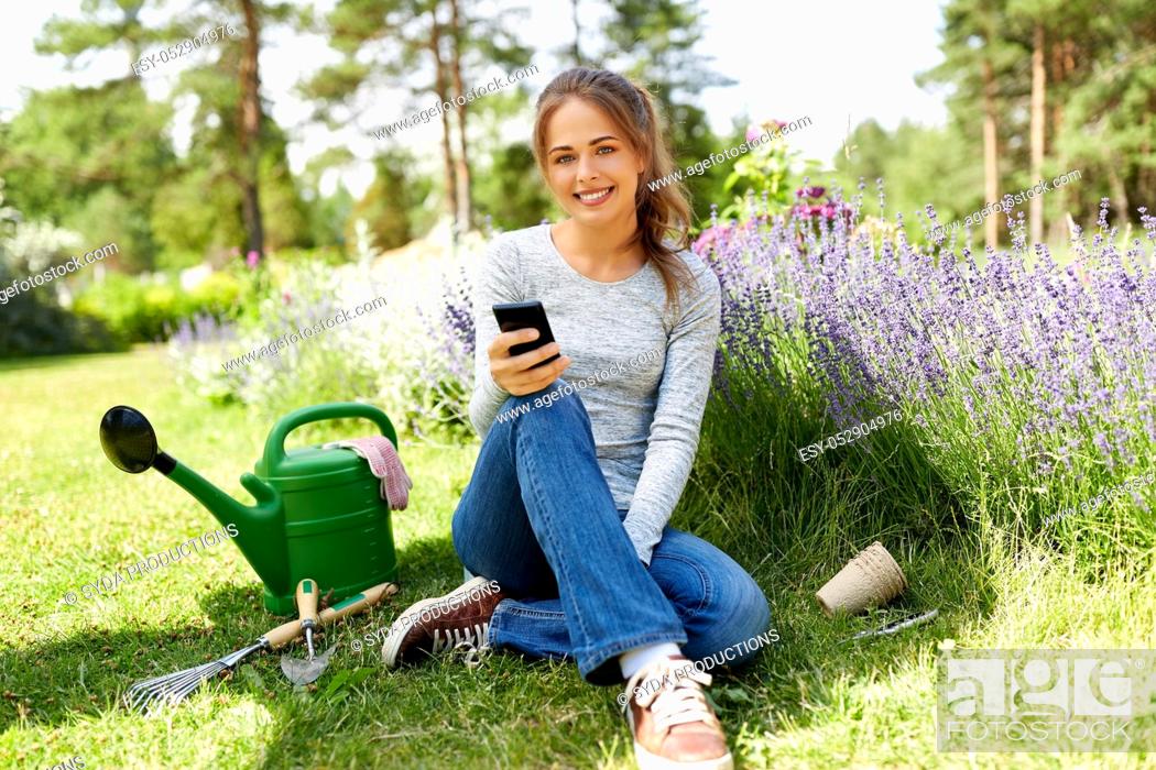 Stock Photo: woman with smartphone and garden tools in summer.