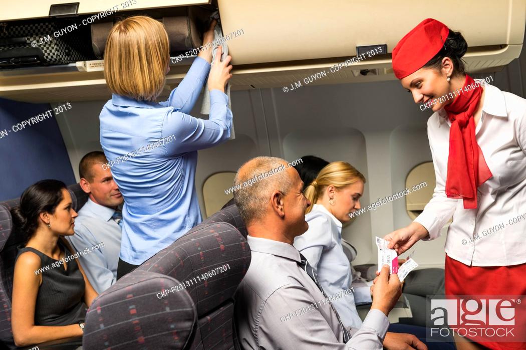 Stock Photo: Air stewardess check passenger ticket in airplane cabin smiling.
