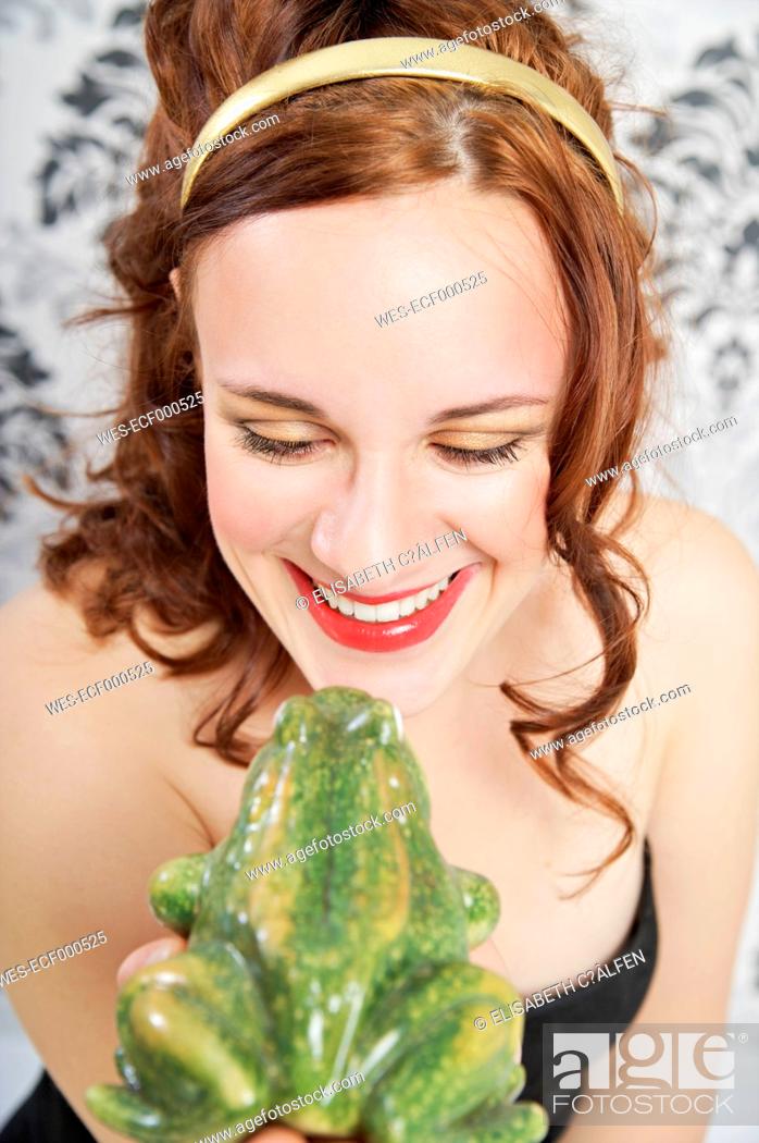 Stock Photo: Portrait of smiling young woman kissing frog.