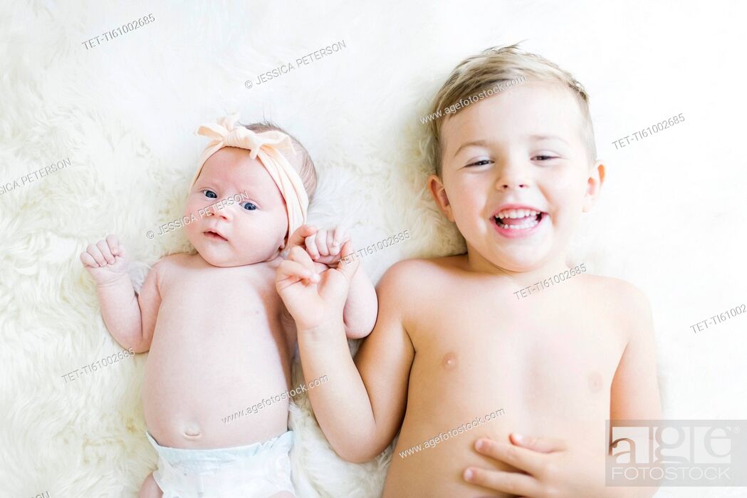 Stock Photo: Brother (4-5) and sister (0-1 months) lying on bed.