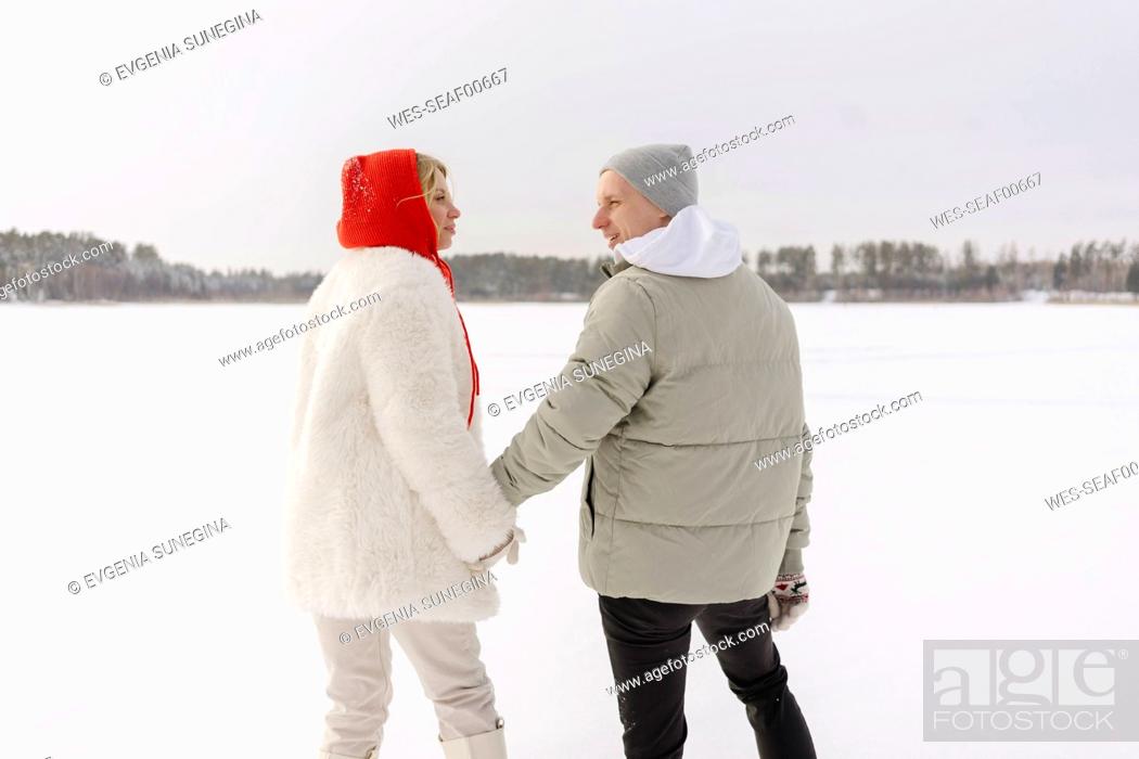 Imagen: Couple holding hands standing on snow in winter.