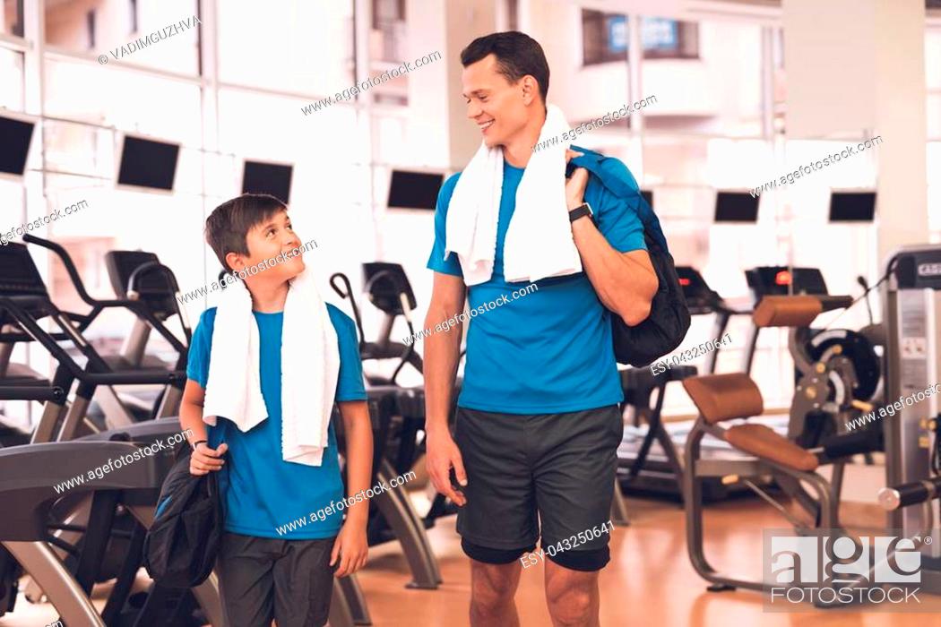 Stock Photo: Father with his son in the same clothes in the gym. Father and son spend time together and lead a healthy lifestyle. A man and a boy are posing in the gym.