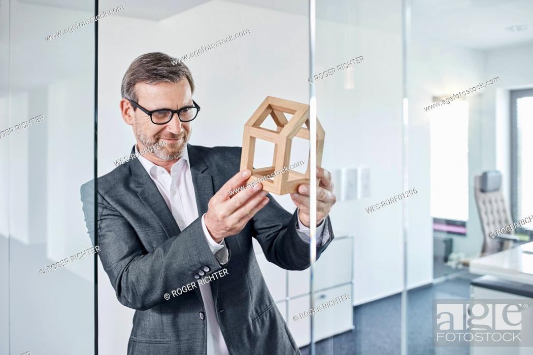Imagen: Smiling businessman looking at architectural model in office.
