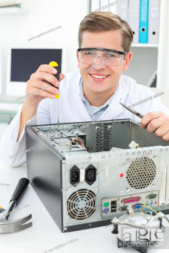 Stock Photo: Happy computer engineer working on broken device.