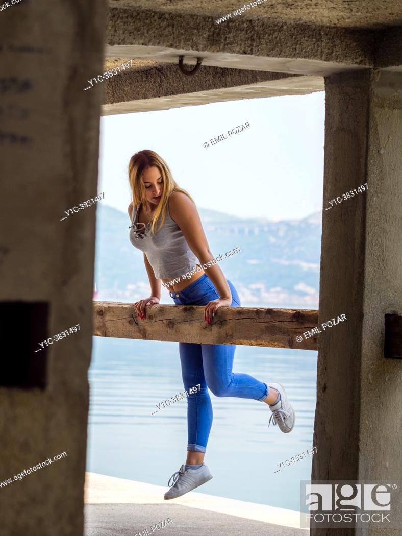 Stock Photo: Teengirl exercising jumping balancing on wooden beam post looking down away.