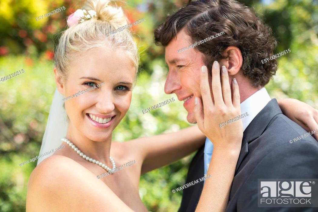 Stock Photo: Pretty wife touching her new husbands cheek smiling at camera.
