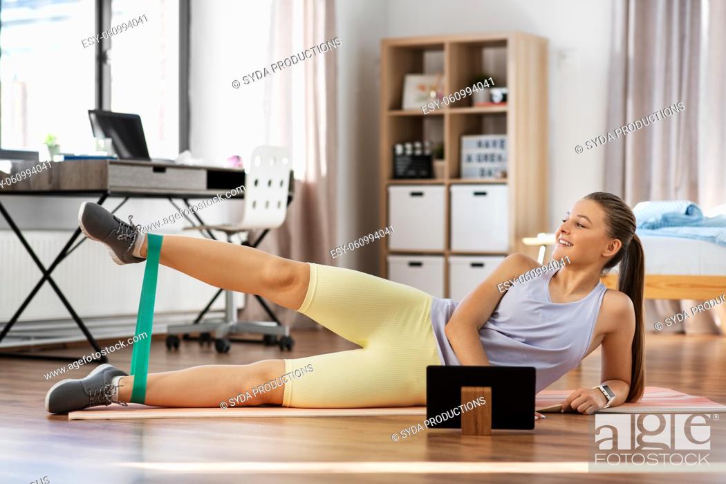 Stock Photo: teenage girl with tablet pc exercising at home.