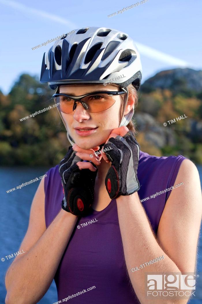 Stock Photo: woman putting on a cycling helmut.