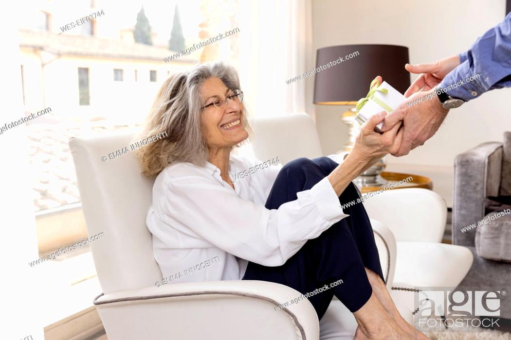 Stock Photo: Happy senior woman receiving gift from man at hotel apartment.