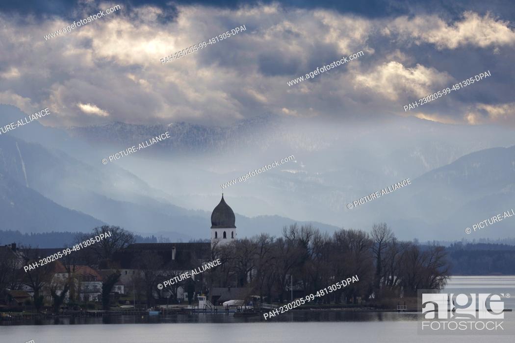 Stock Photo: 05 February 2023, Bavaria, Chiemsee: The bell tower of the Frauenchiemsee monastery complex on Fraueninsel in Lake Chiemsee shows off against the backdrop of.