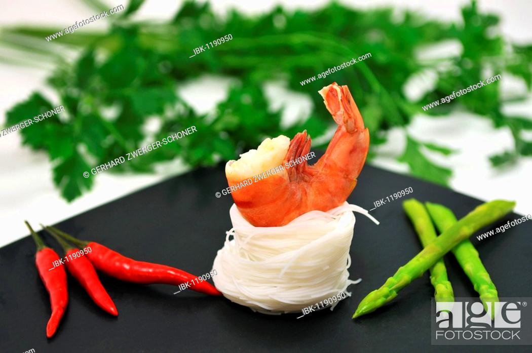 Stock Photo: Scampi on a bed of rice noodles with Thai asparagus and red chilli in front of parsley.