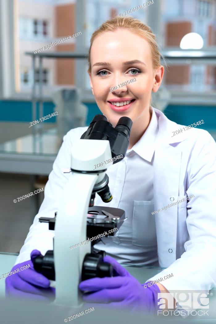 Photo de stock: science, chemistry, technology, biology and people concept - close up of female scientist looking to microscope in clinical laboratory.