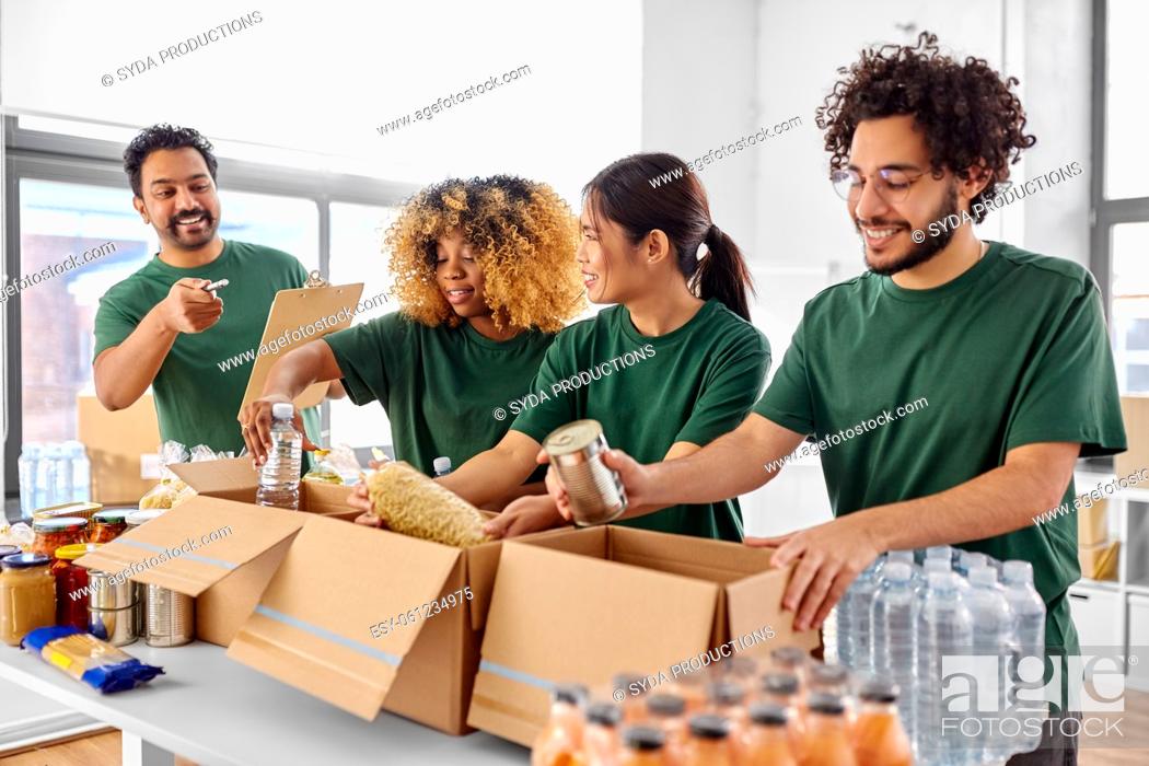 Stock Photo: happy volunteers packing food in donation boxes.