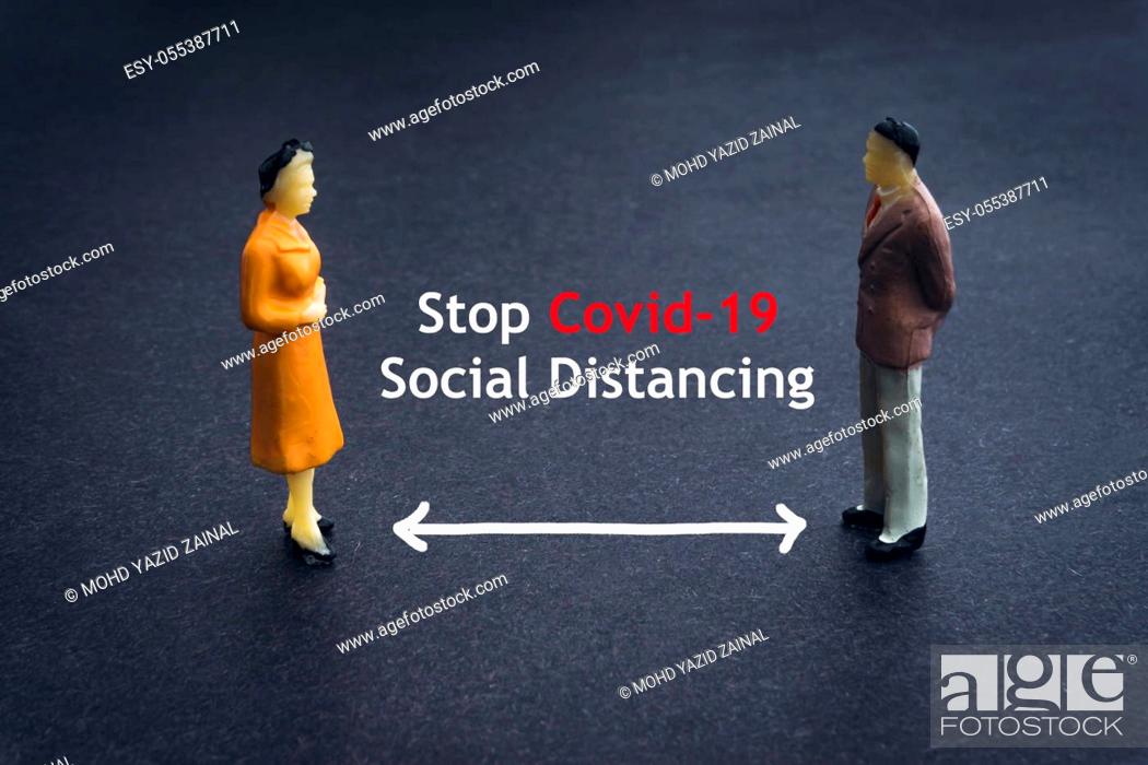 Imagen: STOP COVID-19 SOCIAL DISTANCING text with miniature people on dark background. Covid-19 or Coronavirus concept.