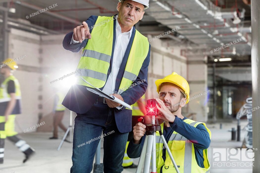 Imagen: Male foreman and engineer with theodolite at construction site.