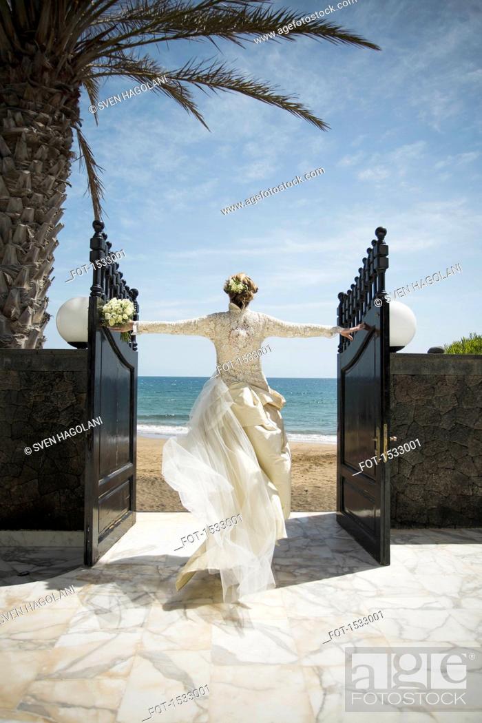 Stock Photo: Rear view of bride opening gate while walking towards beach.
