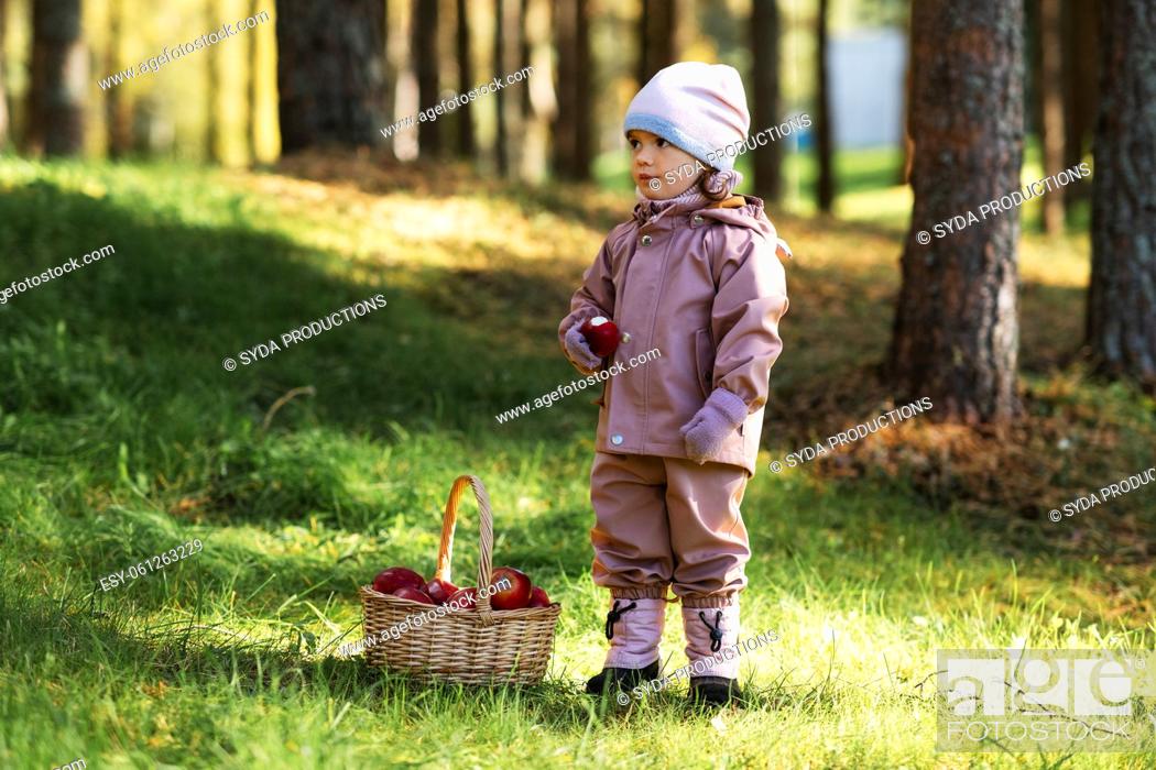 Stock Photo: little baby girl with basket of apples at park.