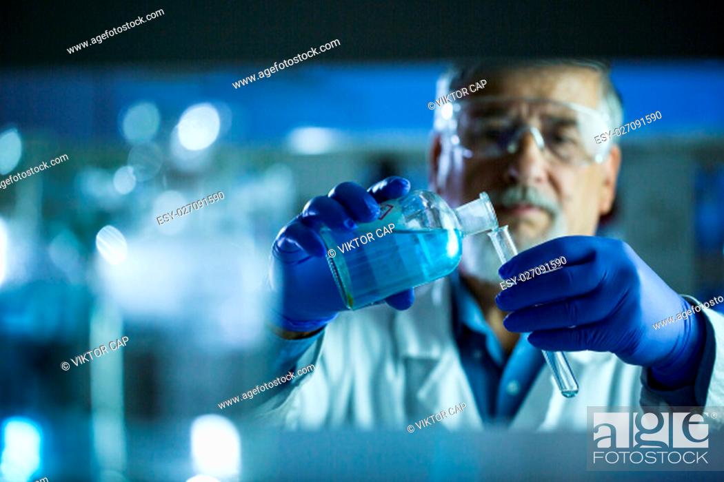 Stock Photo: Senior male researcher carrying out scientific research in a lab (shallow DOF; color toned image).