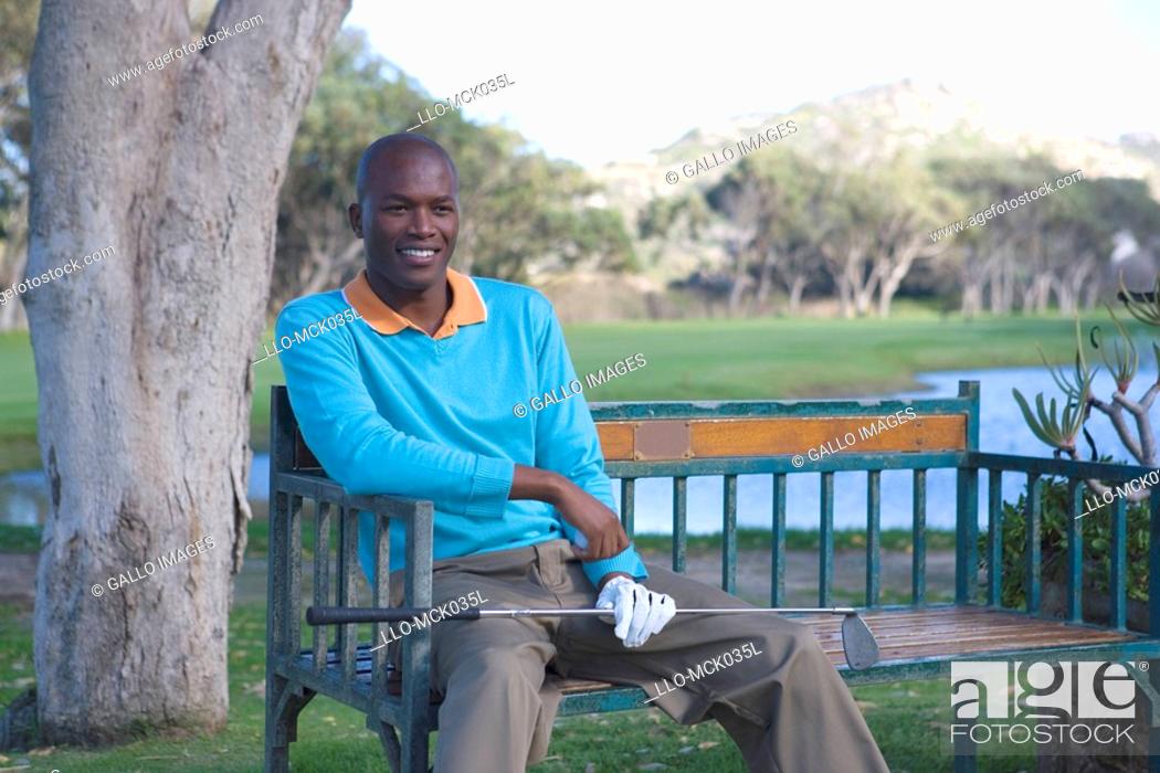 Stock Photo: Man Sitting on Bench with Golf Club  Clovelly Golf Course, Cape Town, Western Province, South Africa.