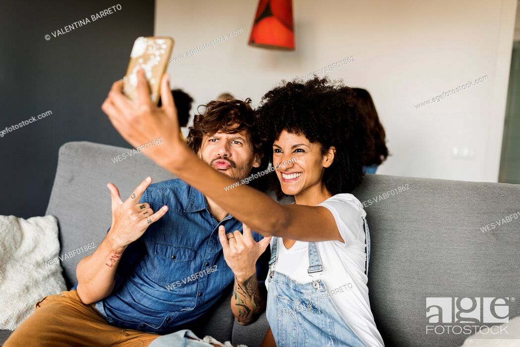 Stock Photo: Happy couple sitting on couch taking a selfie.