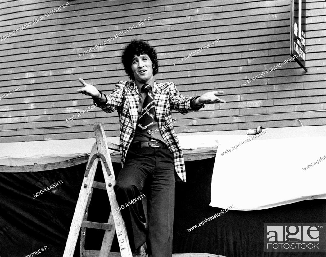 Stock Photo: Ninetto Davoli on a ladder. Italian actor Ninetto Davoli gesticulating on a ladder. Behind him, the sign of a tobacconist. Rome, 1970s.