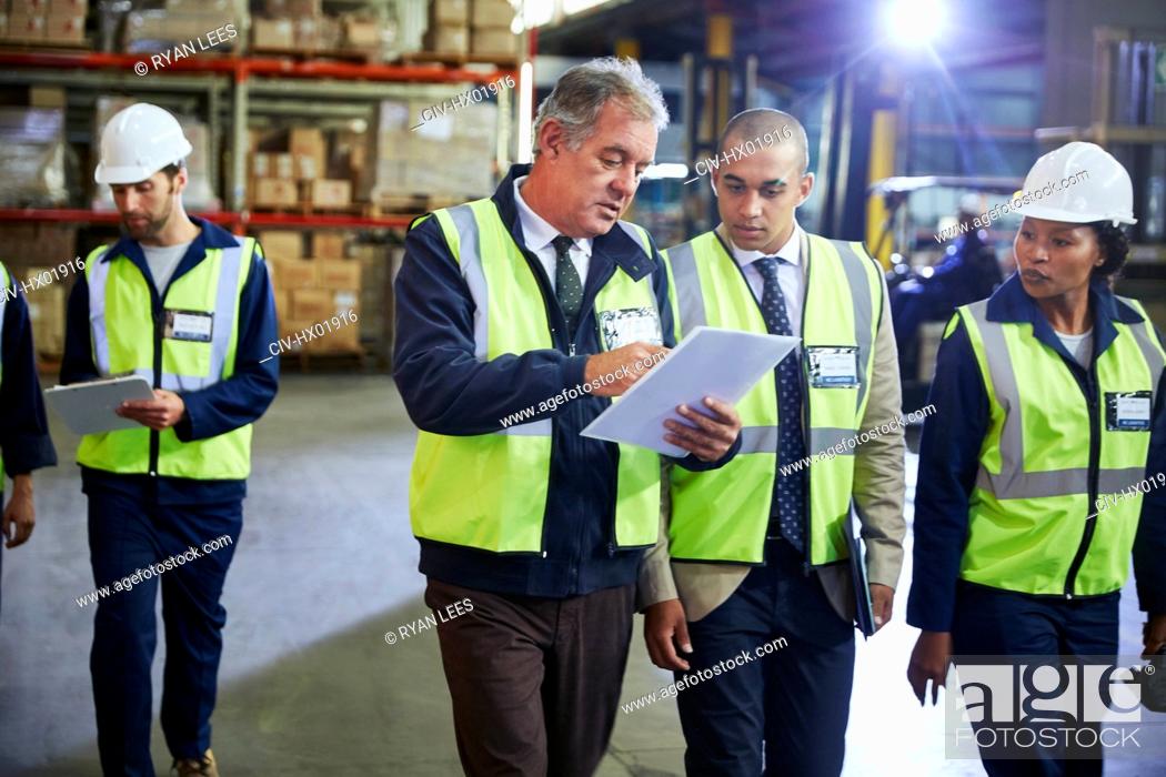 Stock Photo: Manger and workers with clipboard talking in distribution warehouse.