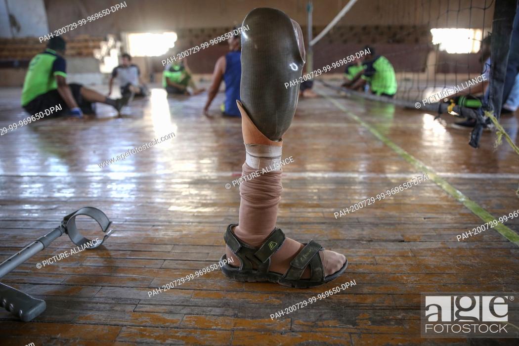 Stock Photo: 25 July 2020, Syria, Idlib City: A picture made available on 30 July 2020 shows a prosthetic leg backdropped by Syrian amputee men taking part in a sitting.