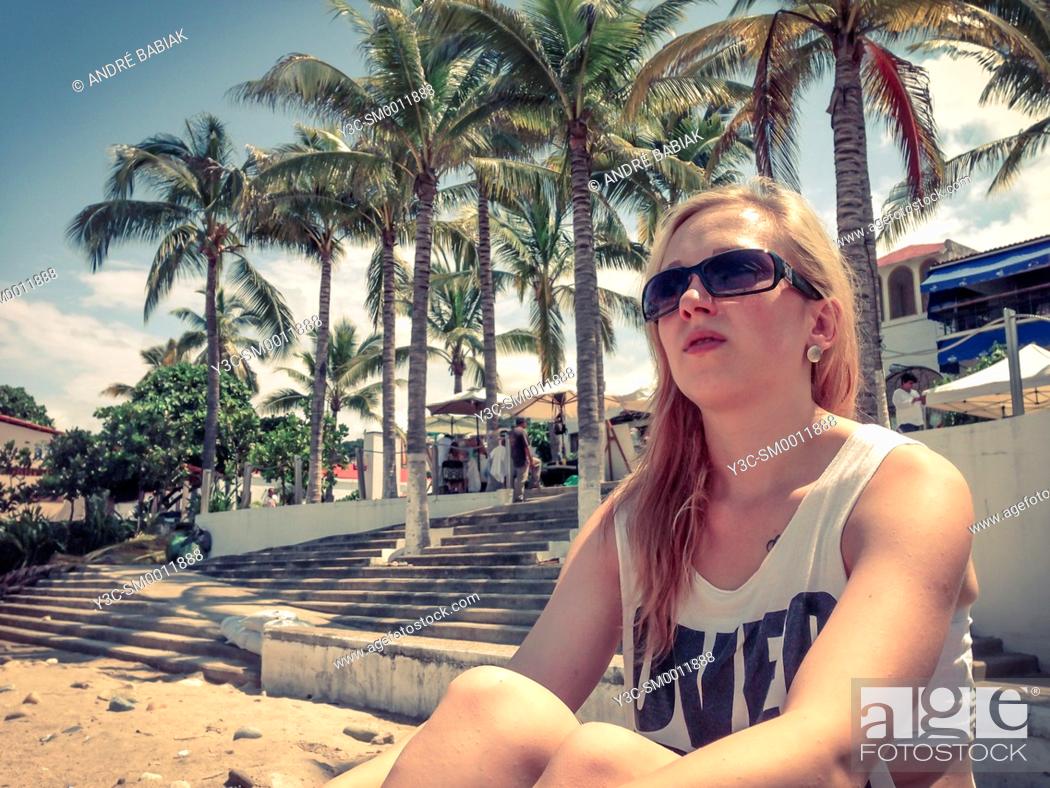 Photo de stock: Young woman sitting at a beach in Puerto Vallarta, Mexico.