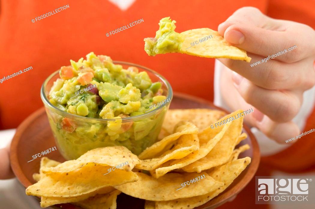 Stock Photo: Woman dipping nacho in guacamole.