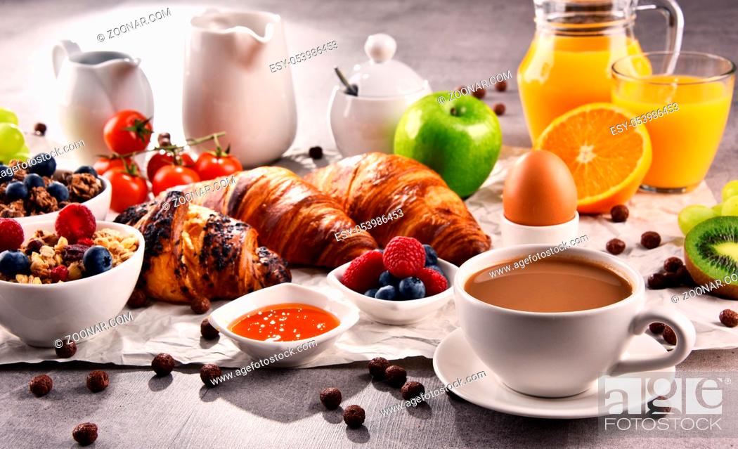 Stock Photo: Breakfast served with coffee, orange juice, croissants, egg, cereals and fruits. Balanced diet.