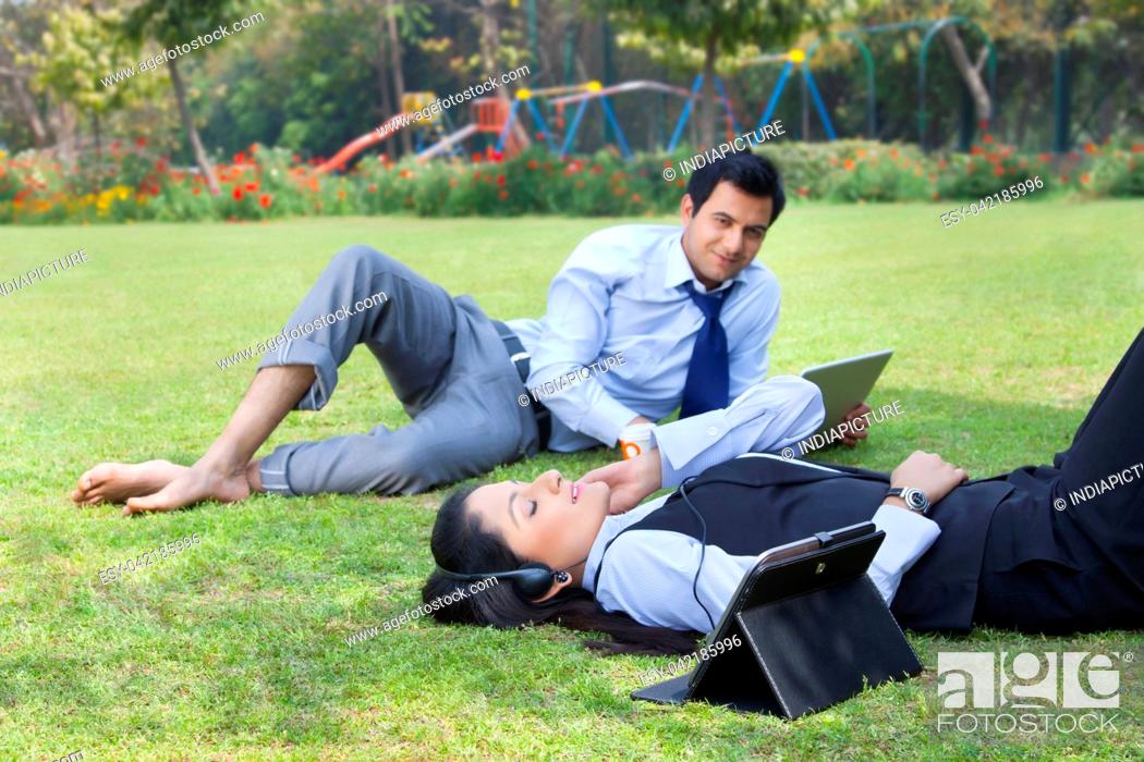 Photo de stock: Businessman working in the park while businesswoman relaxes.