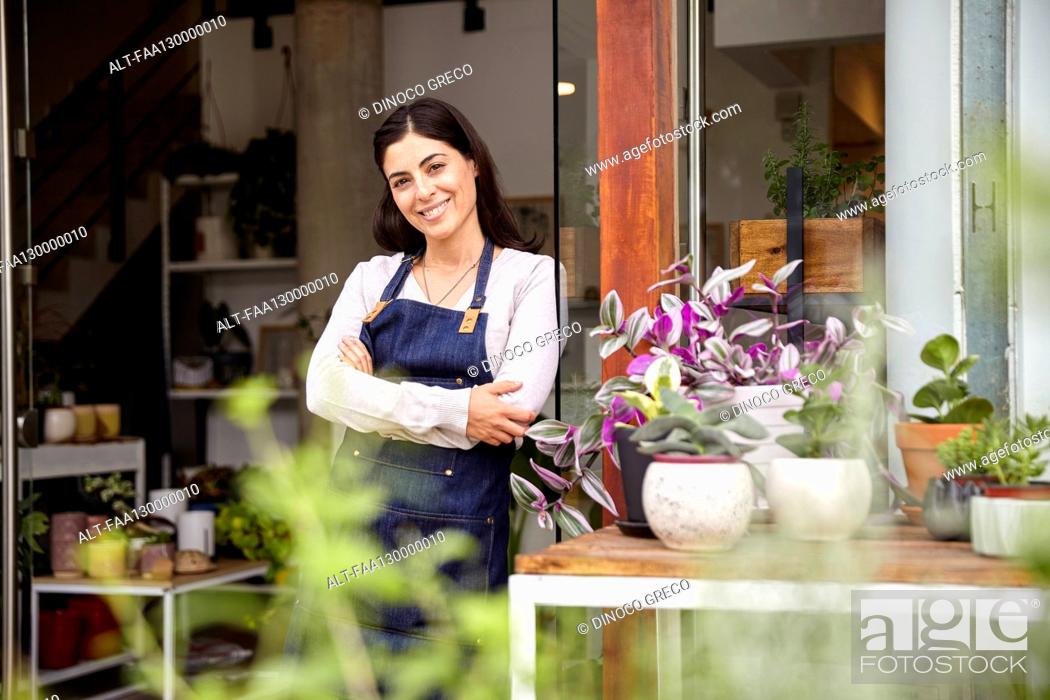 Photo de stock: Plant nursery female owner leaning on entrance while looking at the camera.