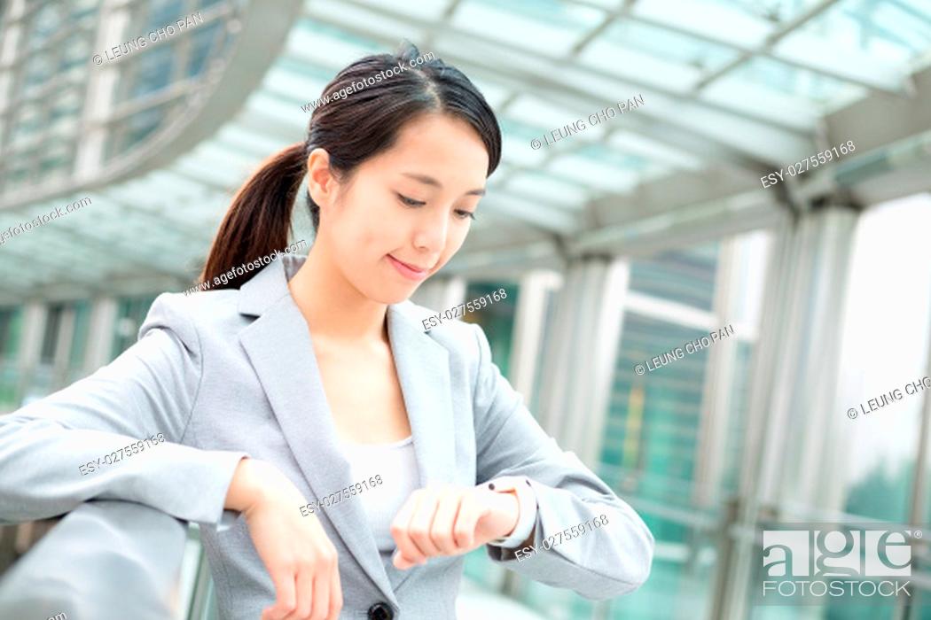 Stock Photo: Asian business woman looking at smart watch.
