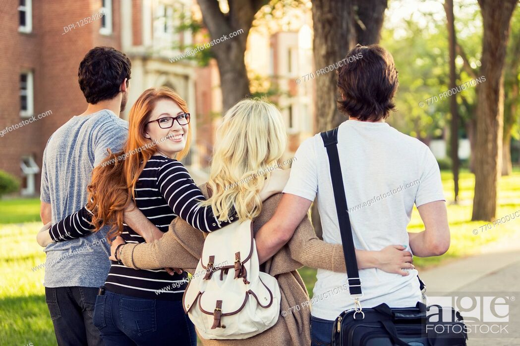 Stock Photo: Four friends walking and talking in an embrace on the university campus with a female looking back at the camera; Edmonton, Alberta, Canada.