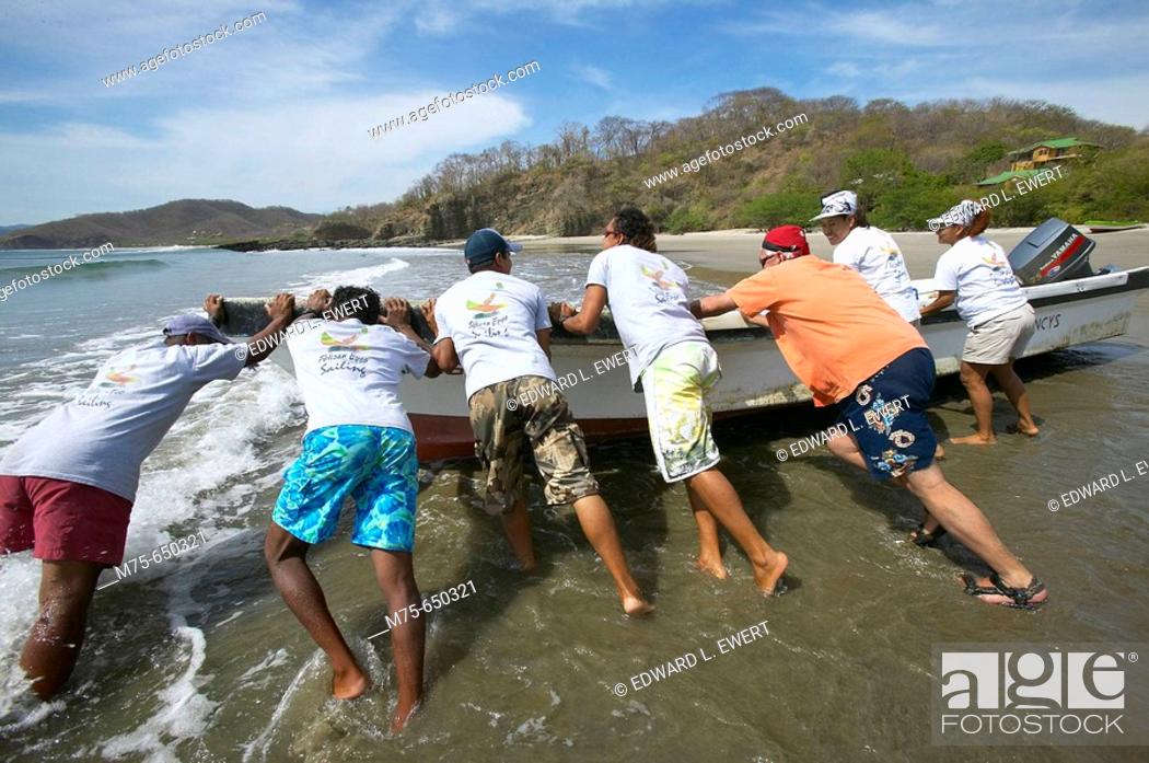Stock Photo: Nicaraguan Boatmen Shoving Off. El Coco beach, Nicaragua.