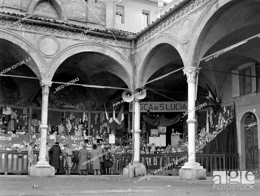 Stock Photo: Some people taking part in the lottery held by a stall under the arcades of the basilica of Santa Maria dei Servi during the Saint Lucy fair.