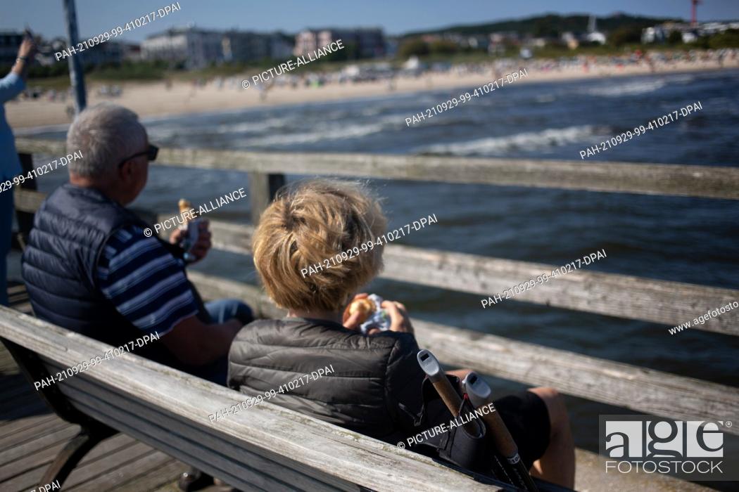 Photo de stock: PRODUCTION - 28 September 2021, Mecklenburg-Western Pomerania, Ahlbeck: A couple takes a break on the pier at the beach of the Baltic resort Ahlbeck on the.