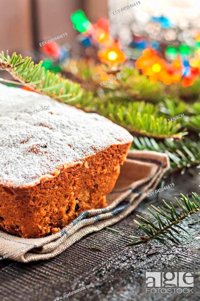 Stock Photo: cake with raisins sprinkled with icing on a wooden table with Christmas tree and Christmas lights.