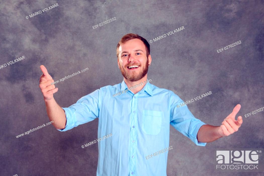 Stock Photo: young bearded man is surprised and showing open hands.