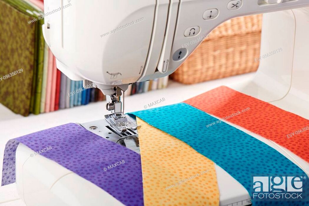 Stock Photo: Sewing machine with a strips of fabrics on the background of stack of colorful quilting fabrics.