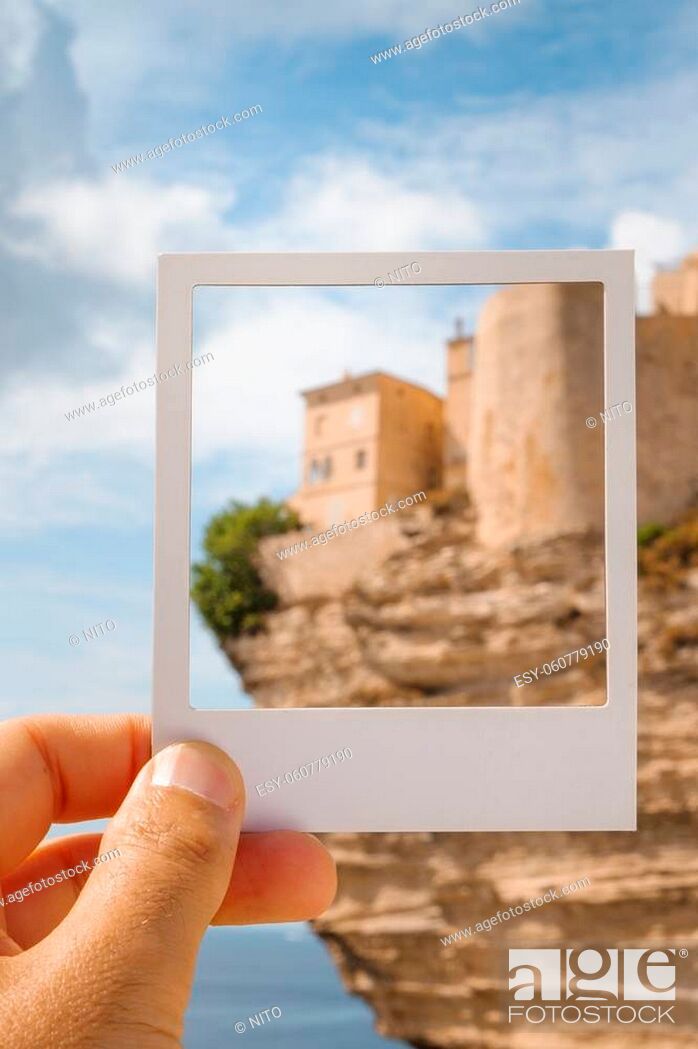 Imagen: closeup of a young man with a white frame in his hand, framing the Haute Ville, the old town of Bonifacio, in Corsica, France, built on the top of a promontory.