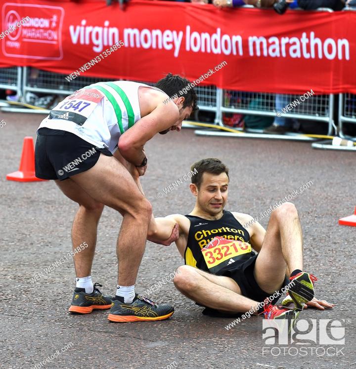 Stock Photo: Matthew Rees (left) of Swansea Harriers unselfishly helps David Wyeth of Chorlton Runners reach the finish line during the Virgin Money London Marathon.