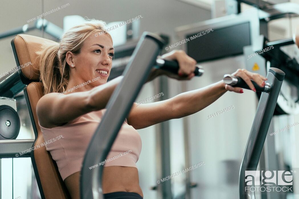 Stock Photo: Chest press workout. Young woman exercising in gym.