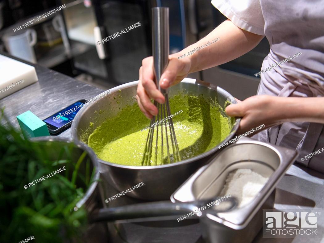 Stock Photo: 26 March 2019, Berlin: A kitchen assistant prepares a sauce in a restaurant kitchen. Photo: Monika Skolimowska/dpa-Zentralbild/ZB.
